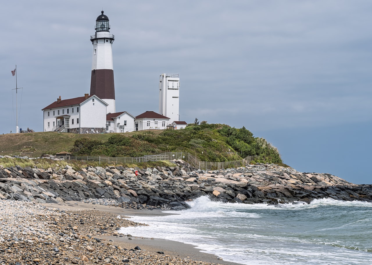 white lighthouse on a grassy hill by the sea